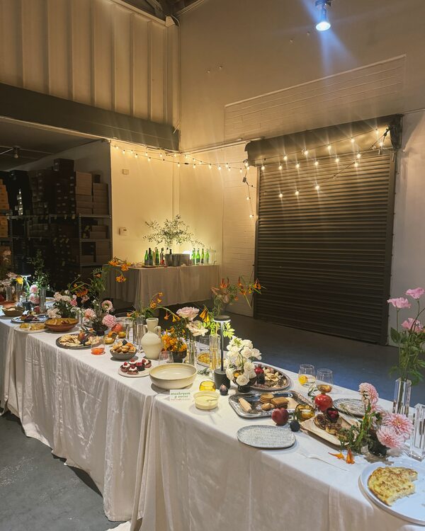 The anniversary table set with flowers, food, and warm lights in the Avarcas USA warehouse